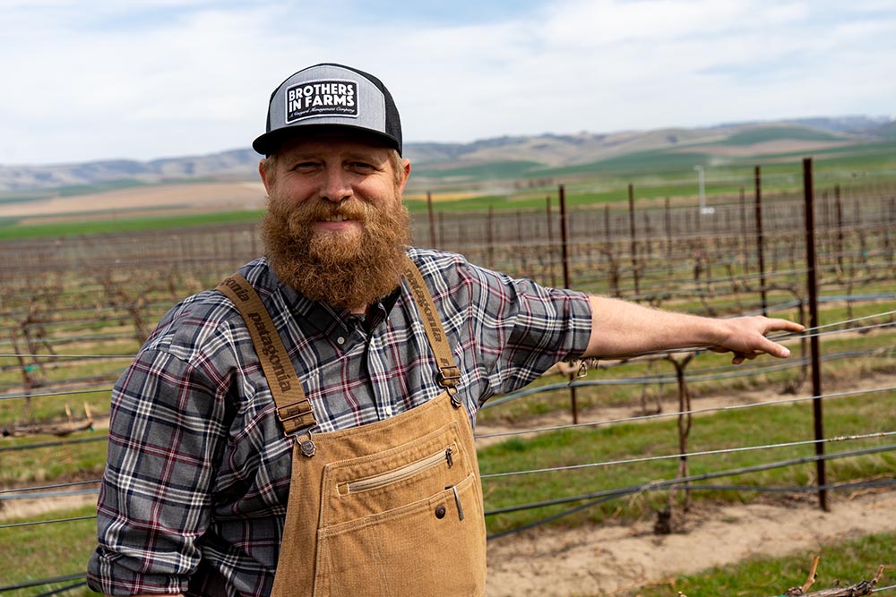 Andrew Schultz standing in a spring vineyard