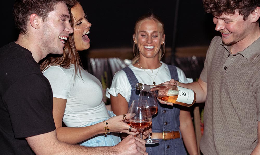 People enjoying wine around a fire.
