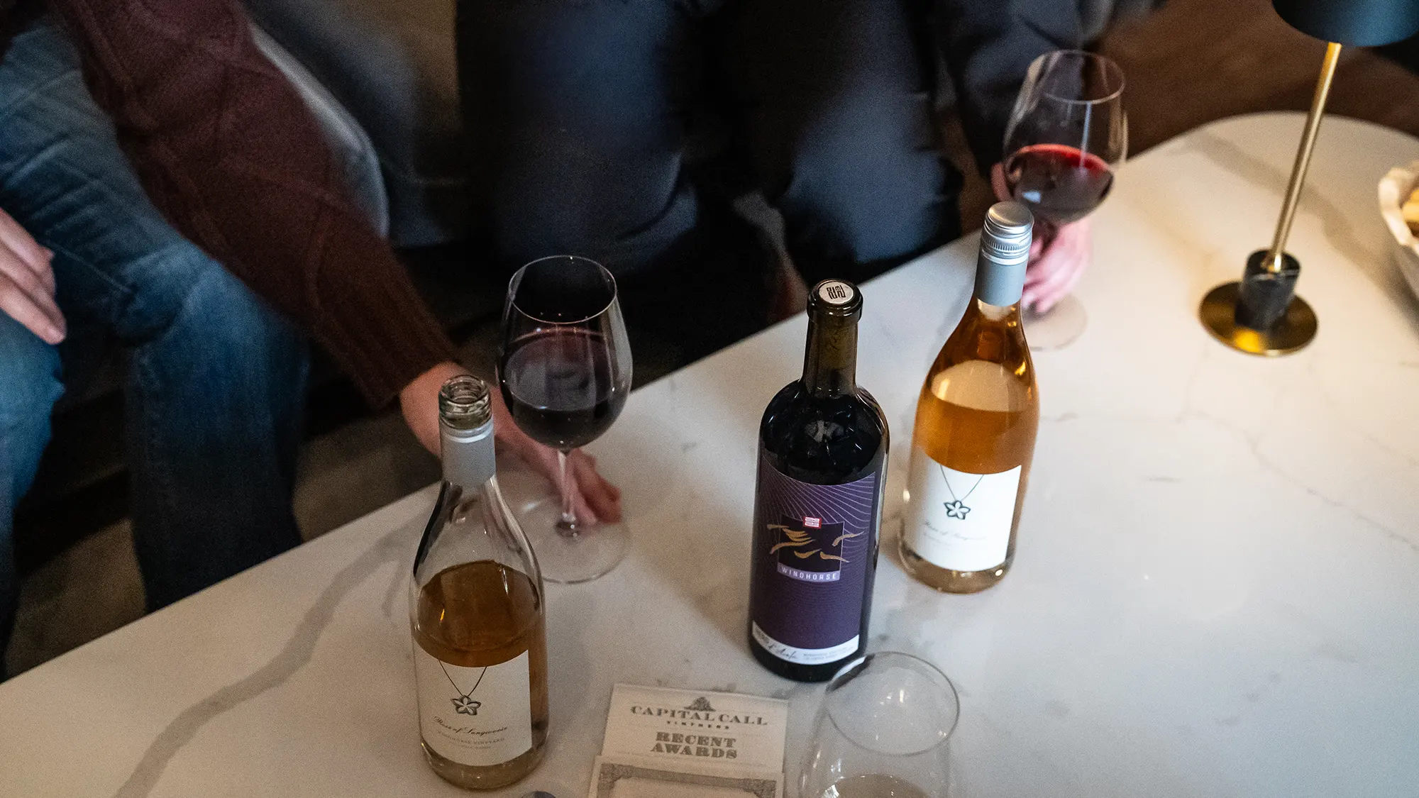 Windhorse Nero d'Avola on table with rose and glasses of wine